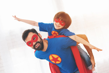 Father and son in the red and blue suits of superheroes. On their faces are masks and they are in...