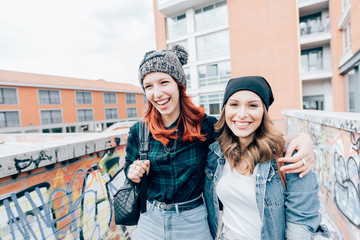 two young women walking outdoors having fun hugging - interaction, happiness, friendship concept