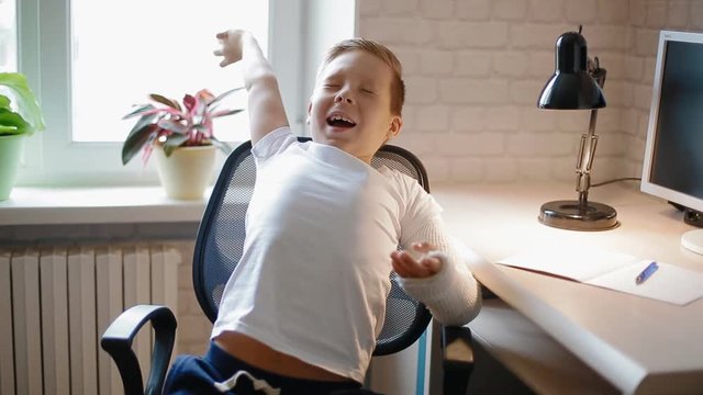 White boy stretching after doing his hometask sitting on the chair.