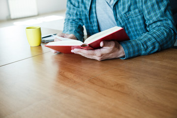 man reading book with cup of tea or coffee at home