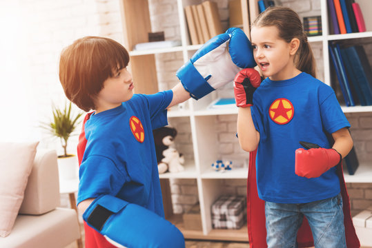 Children in the red and blue suits of superheroes. They in masks. Kids posing in bright room.