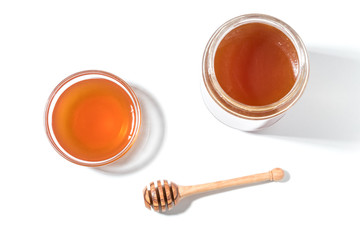 Honey dipper and honey in jar on white background.