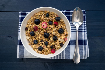 Breakfast granola cereal bowl with fruit and berries and spoon