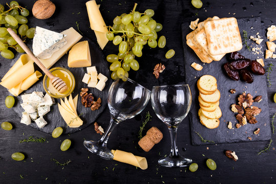 Cheese plate. Assortment of cheese with walnuts, bread an honey on stone slate plate.