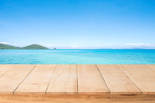 wood terrace over blue sea and tropical island beach background.