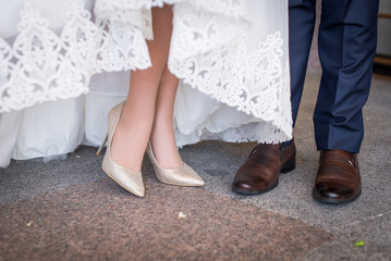 Legs and feet of married couple in stylish shoes. Women's high heel shoes and men's brown shoes