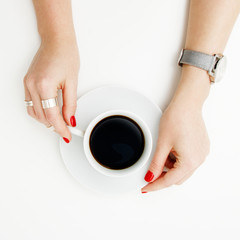 Flat lay. Top view. Minimal style. Minimalist Fashion and beauty photography. Morning mood. A girl in a sweater manicure holds a white cup of coffee on a white table background. Watches and jewelry