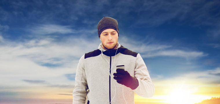 happy man with earphones and smartphone in winter