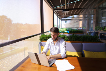 Copywriter typing text on laptop at cafe table.