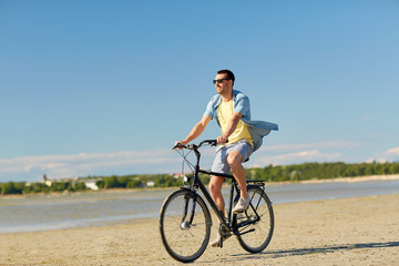 Fototapeta na wymiar happy man riding bicycle along summer beach