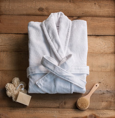 bathrobe bath soap and loofah brush behind wooden table wooden backgorund - obrazy, fototapety, plakaty