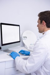 Side view of dentist working on computer