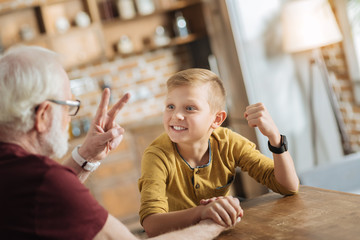 Armwrestling game. Positive happy nice grandfather and grandson looking at each other and having fun while doing armwrestling