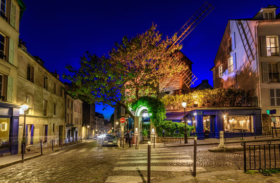 Night view of cozy street with old mill in quarter Montmartre in Paris, France