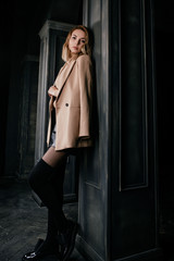Portrait of young attractive pretty blonde woman in the beige jacket and leather shirt, gaiters,...