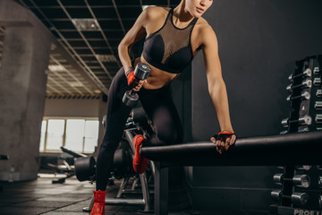 Fototapeta na wymiar Keeping her body fit. Close-up of beautiful young woman with fit body exercising with dumbbells while standing against black background