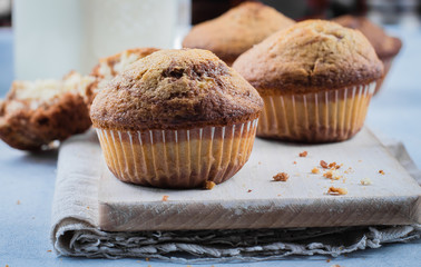 Homemade sweet chocolate vanilla muffins from two types of dough with mason jar of milk on on wooden board on blue stone table background