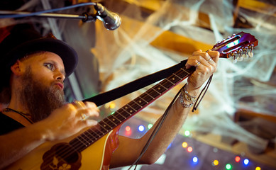  eccentric man in a hat performs at a music bar. Sings songs and plays Irish bouzouki (girar) - obrazy, fototapety, plakaty