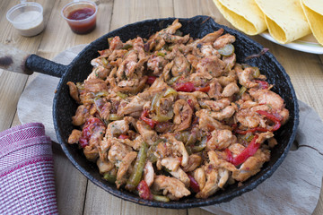 Chicken stew with red and green pepper, with red onion, pickled cucumber and spices in a frying pan.
