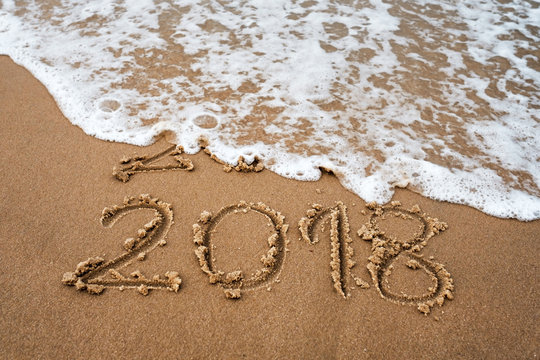 Happy New Year 2018 replace 2017. Inscription on seashore during travel. Water is moving away numbers