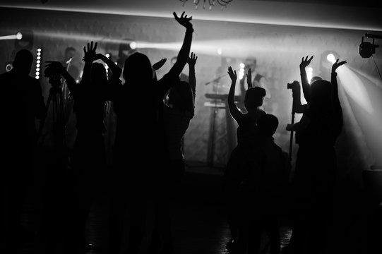 Musicial music live band performing on a stage with different lights with crowd of people fans.