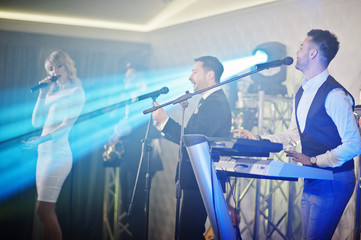 Musicial music live band performing on a stage with different lights.
