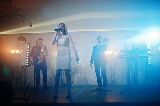 Musicial music live band performing on a stage with different lights.