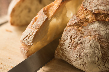 Pieces of white crisp bread are cut with a kitchen knife on a wooden board. Concept: healthy basic food.