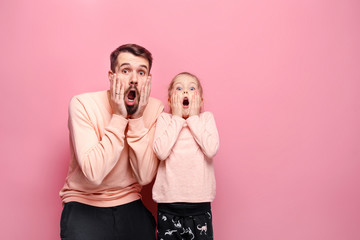 Surprised young family looking at camera on pink