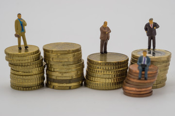 Miniature people sitting on stack coins