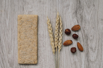 Background with crispbread of wheat grains, almonds hazelnuts and ears of wheat on a wooden background. Healthy food.