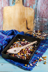 Beans mix in the jar and tray. Blue wooden table and background.