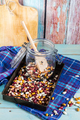 Beans mix in the jar and tray. Blue wooden table and background.