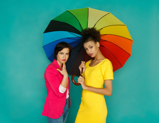 Two worried girlfriends posing at azur studio background
