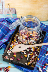 Beans mix in the jar and tray. Blue wooden table and background.