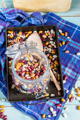 Beans mix in the jar and tray. Blue wooden table and background.