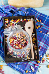 Beans mix in the jar and tray. Blue wooden table and background.