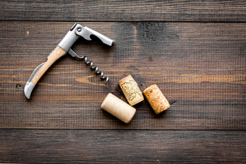 Open wine bottle. Corks and corkscrew on dark wooden background top view copyspace