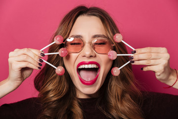 Excited screaming woman wearing glasses holding a lot of sweeties.