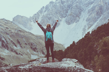 Obraz premium Back view of woman with arms raised in the mountains