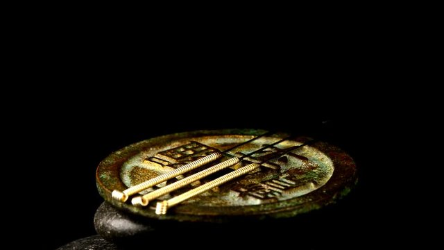 Akupunkturnadeln auf antiker chinesischer Münze auf einem Drehteller
