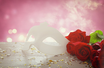 Valentines day romantic background with beautiful bouquet of roses and masquerade white mask on...