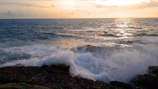 ocean wave crashing on the rock at sunset. slow motion