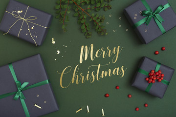 Christmas gifts on dark green background with greeting message, Merry Christmas, written in the middle