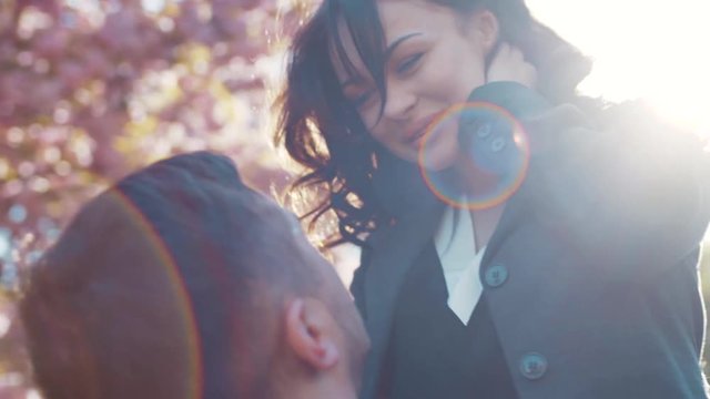 Few shots of young couple in love having fun in the city park, he holds her on his hands and whirls, they are laughing. True emotions, love story, romantic date