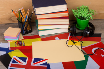Learning languages concept - blank paper, flags, books, headphones, pencils on wooden background