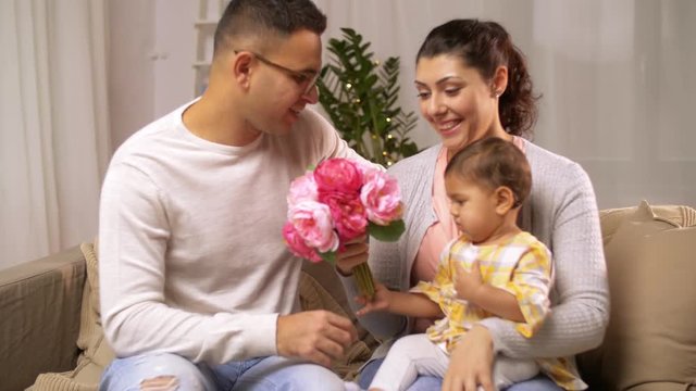 happy family with baby girl and flowers at home