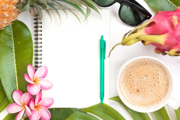 Tropical top view summer botanical concept still life sunglasses pineapple coffee cup notebook dragon fruit frame with monstera liana, vine, palm leaves and plumeria frangipani flower flat lay layout