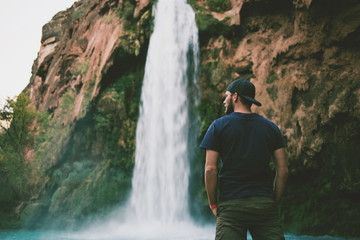 Man in front of beautiful blue waterfall