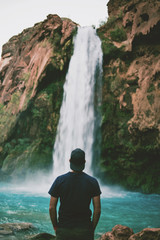 Man in front of beautiful blue waterfall
